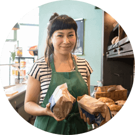 Symbolfoto: Eine Bäckereifachkraft hält zwei Papiertüten in den Händen